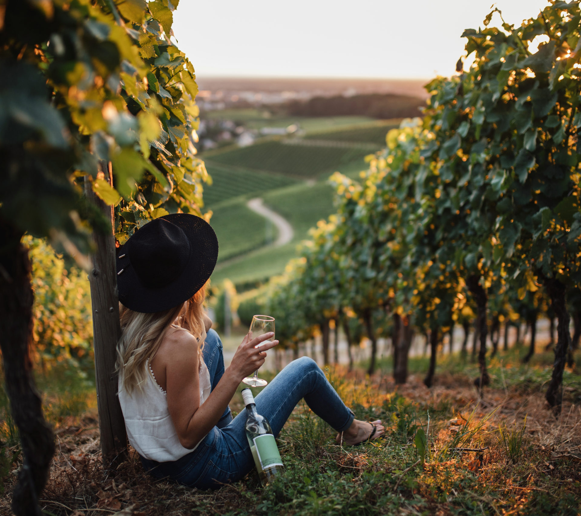 young-blonde-woman-relaxing-vineyards-summer-season-with-bottle-wine